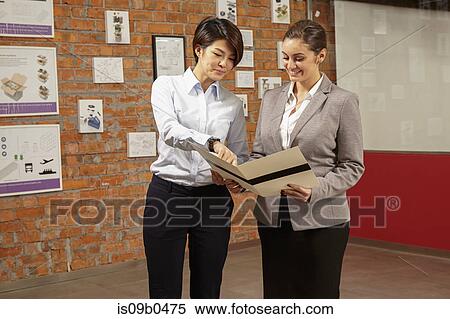 Female asian worker showing caucasian female manager print brochure in gallery of printing and packaging factory, China View Large Photo Image Stock Photography - Female asian worker showing caucasian female manager print brochure in gallery of printing and packaging factory, China. Fotosearch