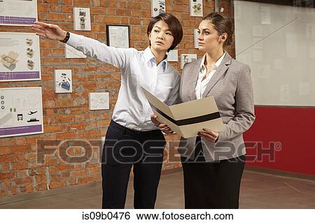 Female asian worker showing prints to caucasian female manager in gallery of printing and packaging factory, China View Large Photo Image Stock Photograph - Female asian worker showing prints to caucasian female manager in gallery of printing and packaging factory, China. Fotosearch