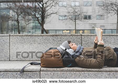 Female backpacker lying on back reading book on wall View Large Photo Image Stock Image - Female backpacker lying on back reading book on wall. Fotosearch