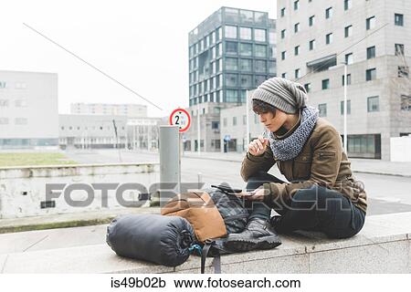 Female backpacker sitting on wall looking at notebook View Large Photo Image Stock Image - Female backpacker sitting on wall looking at notebook. Fotosearch