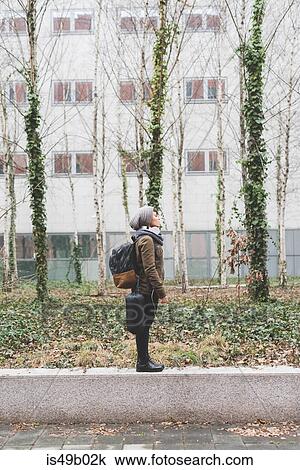 Female backpacker standing on office buildings wall View Large Photo Image Stock Image - Female backpacker standing on office buildings wall. Fotosearch