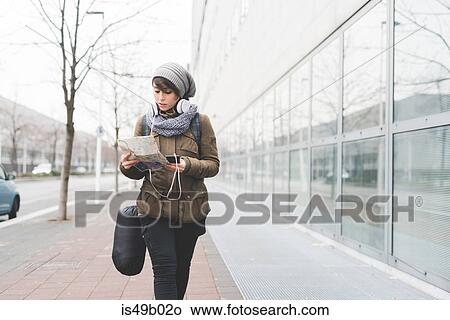 Female backpacker with smartphone looking at map on city sidewalk View Large Photo Image Picture - Female backpacker with smartphone looking at map on city sidewalk. Fotosearch