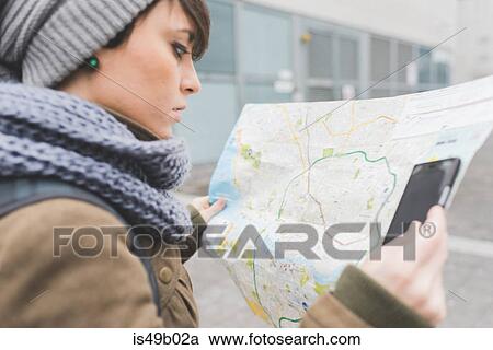 Stock Image - Female backpacker with smartphone looking at map in city. Fotosearch