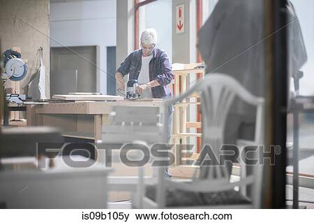 Stock Photo - Female carpenter using sander in furniture making workshop. Fotosearch