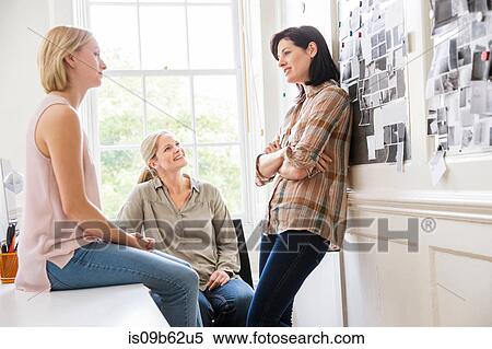 Stock Photography - Female design team discussing ideas at creative studio meeting. Fotosearch