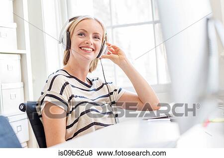Female designer listening to headphones at creative studio desk View Large Photo Image Stock Photo - Female designer listening to headphones at creative studio desk. Fotosearch