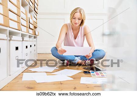 Stock Photo - Female designer sitting on floor creating mood board in creative studio. Fotosearch