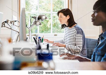 Stock Photo - Female designers at desktop computers in creative studio. Fotosearch