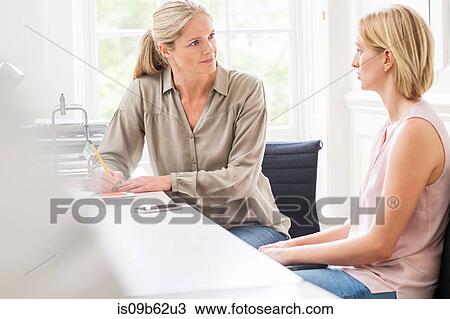 Stock Image - Female designers having discussion at creative studio meeting. Fotosearch