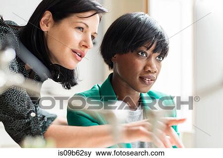 Female designers pointing at computer in creative studio View Large Photo Image Stock Photo - Female designers pointing at computer in creative studio. Fotosearch