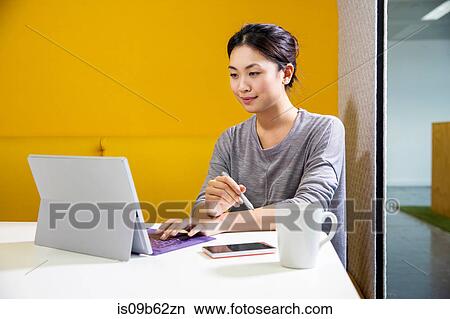 Picture - Female digital designer at office desk using laptop. Fotosearch