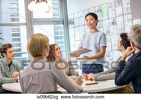 Female digital designer explaining ideas to team at conference table View Large Photo Image Stock Image - Female digital designer explaining ideas to team at conference table. Fotosearch