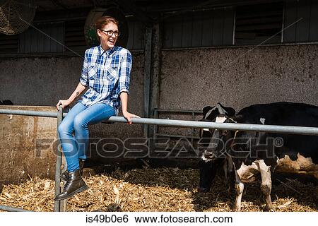 Female farmer sitting on fence at organic dairy farm View Large Photo Image Stock Photograph - Female farmer sitting on fence at organic dairy farm. Fotosearch