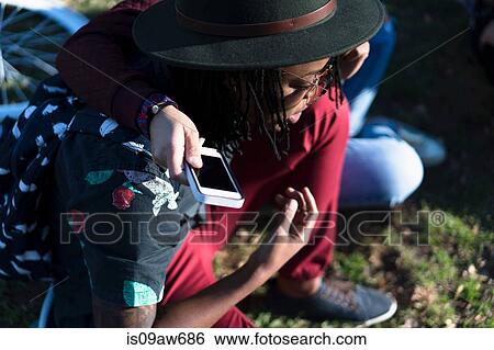 Female friends outdoors, holding smartphone View Large Photo Image Stock Photograph - Female friends outdoors, holding smartphone. Fotosearch