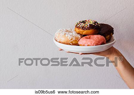 Stock Photograph - Female hand holding plate of doughnut holes. Fotosearch