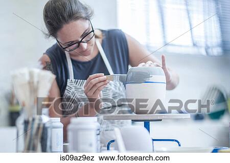 Female potter painting ceramic glaze on vase in workshop View Large Photo Image Stock Photo - Female potter painting ceramic glaze on vase in workshop. Fotosearch