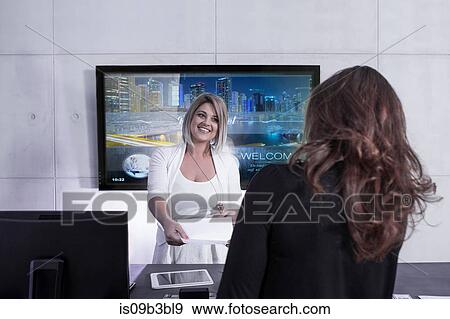 Female receptionist handing reservation to woman at hotel reception desk View Large Photo Image Stock Photo - Female receptionist handing reservation to woman at hotel reception desk. Fotosearch