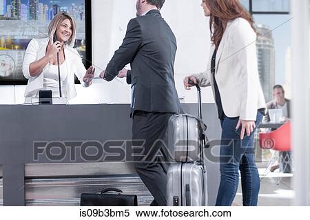 Female receptionist handing reservation to businessman and woman at hotel reception desk View Large Photo Image Stock Photography - Female receptionist handing reservation to businessman and woman at hotel reception desk. Fotosearch