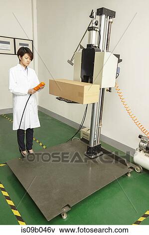 Stock Photo - Female technician operating packaging machine in printing and packaging factory, China. Fotosearch