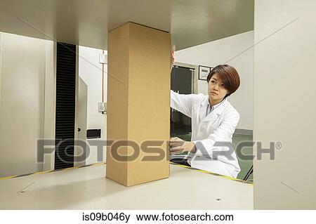 Female technician placing cardboard box on packaging machine in printing and packaging factory, China View Large Photo Image Stock Photo - Female technician placing cardboard box on packaging machine in printing and packaging factory, China. Fotosearch
