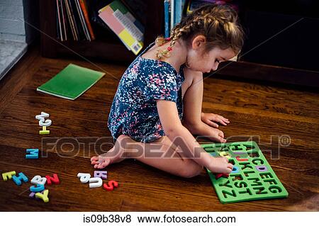 Stock Photo - Female toddler sitting on floor playing with alphabet educational toy. Fotosearch