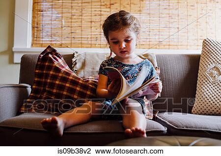 Female toddler sitting on sofa reading storybook View Large Photo Image Stock Image - Female toddler sitting on sofa reading storybook. Fotosearch