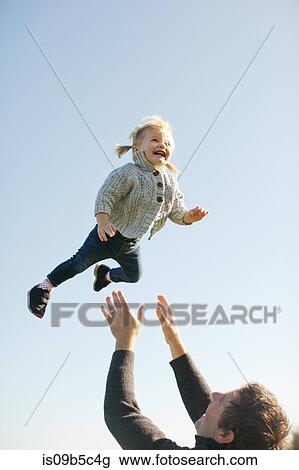 Female toddler thrown mid air by father against blue sky View Large Photo Image Stock Image - Female toddler thrown mid air by father against blue sky. Fotosearch