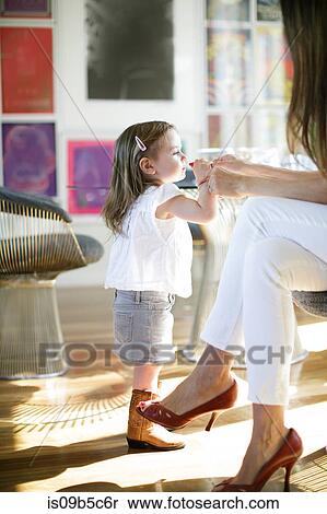 Stock Photography - Female toddler trying mother's lipstick. Fotosearch