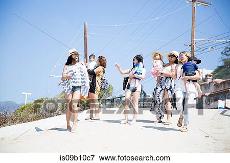 Stock Photo - Four adult female friends and their babies strolling along beach, Malibu, California, USA. Fotosearch