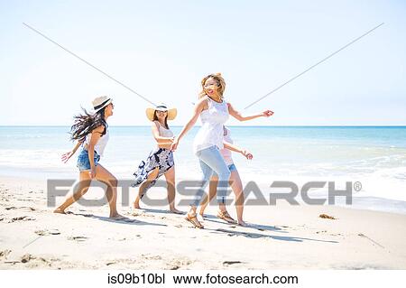 Stock Image - Four adult female friends fooling around on beach, Malibu, California, USA. Fotosearch