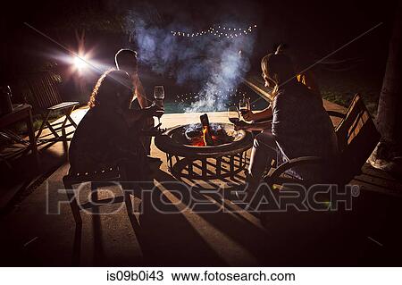 Four mature adults sitting together around patio fire at night View Large Photo Image Stock Image - Four mature adults sitting together around patio fire at night. Fotosearch