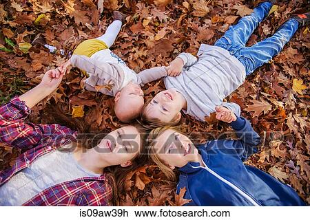 Stock Image - Four siblings lying on autumn leaves. Fotosearch