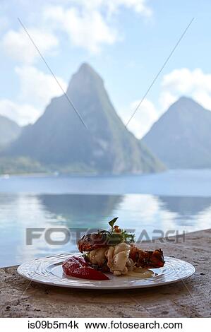 Stock Image - Fresh local lobster dish with view of the Pitons, Saint Lucia, Caribbean. Fotosearch