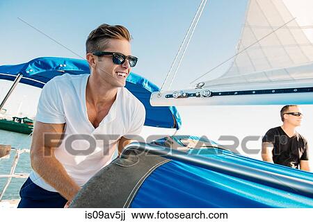 Stock Image - Friends enjoying view on sailboat. Fotosearch