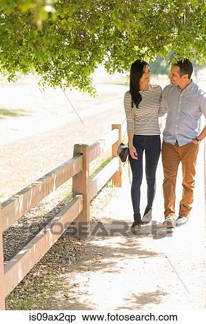 Full length front view of couple strolling on fenced path View Large Photo Image Stock Photography - Full length front view of couple strolling on fenced path. Fotosearch