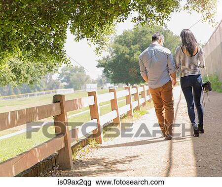 Full length rear view of couple strolling along fenced path View Large Photo Image Stock Image - Full length rear view of couple strolling along fenced path. Fotosearch