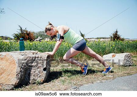 Full length side view of woman wearing activity tracker stretching against rock View Large Photo Image Stock Photograph - Full length side view of woman wearing activity tracker stretching against rock. Fotosearch