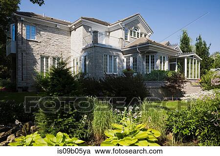 Garden border in landscaped backyard and rear view of grey brick and stone cottage style home in summer, Quebec, Canada View Large Photo Image Stock Image - Garden border in landscaped backyard and rear view of grey brick and stone cottage style home in summer, Quebec, Canada. Fotosearch