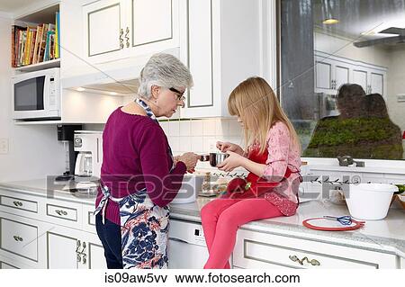 Girl and grandmother looking into saucepan at kitchen counter View Large Photo Image Stock Photo - Girl and grandmother looking into saucepan at kitchen counter. Fotosearch