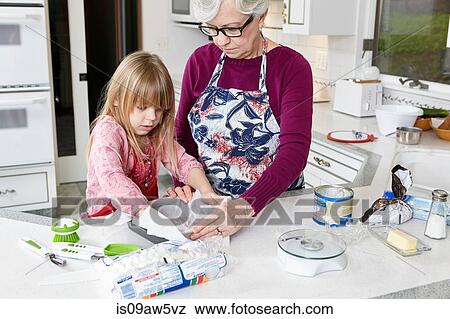 Girl and grandmother preparing greaseproof paper in baking tray View Large Photo Image Stock Photo - Girl and grandmother preparing greaseproof paper in baking tray. Fotosearch