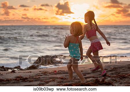 Stock Photography - Girl and sister running on beach at sunrise, Blowing Rocks Preserve, Jupiter Island, Florida, USA. Fotosearch