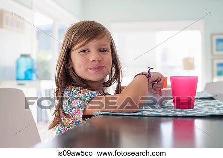 Girl at dining table eating breakfast looking at camera smiling View Large Photo Image Picture - Girl at dining table eating breakfast looking at camera smiling. Fotosearch