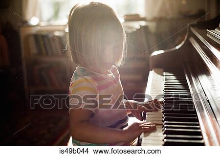 Picture - Girl at home playing old piano. Fotosearch