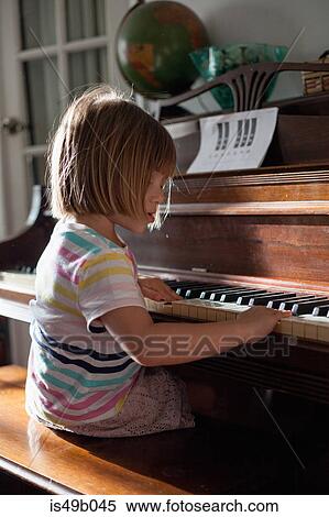 Stock Photography - Girl at home playing old piano. Fotosearch