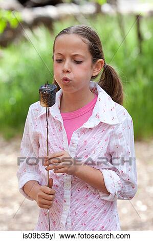 Girl blowing toasted marshmallow in forest, Sedona, Arizona, USA View Large Photo Image Stock Image - Girl blowing toasted marshmallow in forest, Sedona, Arizona, USA. Fotosearch