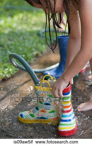 Girl filling wellies with water from hose View Large Photo Image Stock Image - Girl filling wellies with water from hose. Fotosearch