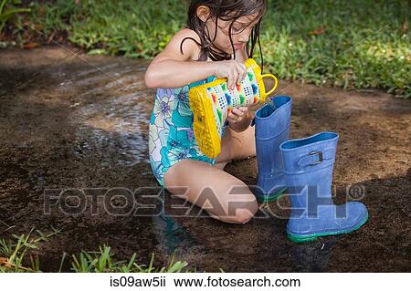 Girl filling wellies with water View Large Photo Image Stock Image - Girl filling wellies with water. Fotosearch