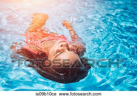 Girl floating on her back in sunlit swimming pool View Large Photo Image Stock Image - Girl floating on her back in sunlit swimming pool. Fotosearch