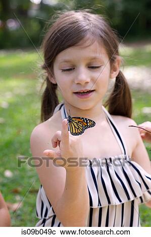 Stock Image - Girl holding monarch butterfly on finger. Fotosearch