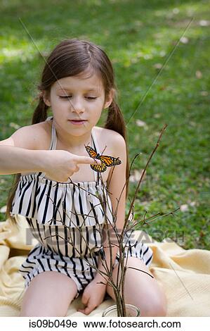 Stock Image - Girl holding monarch butterfly on finger. Fotosearch